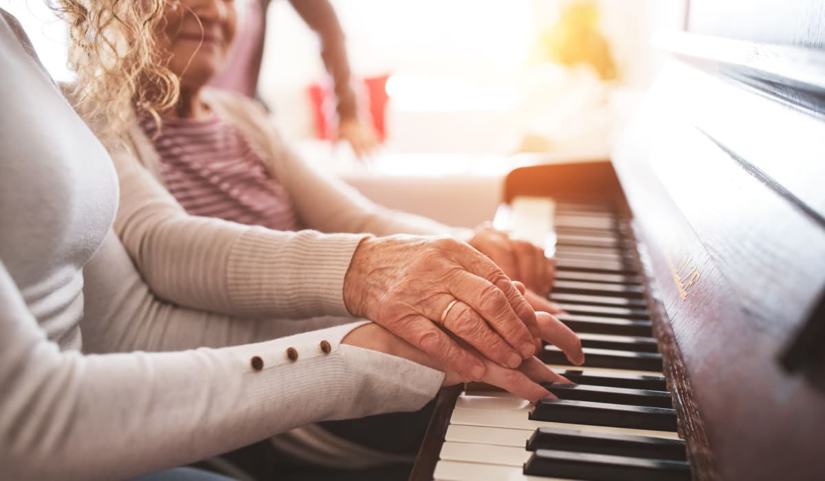 A resident and staff member playing the piano at CERTUS Premier Memory Care Living in Orange City, Florida.