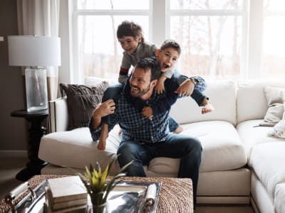 Boys wrestle with their Dad on the couch at Courtyard in Hayward, California