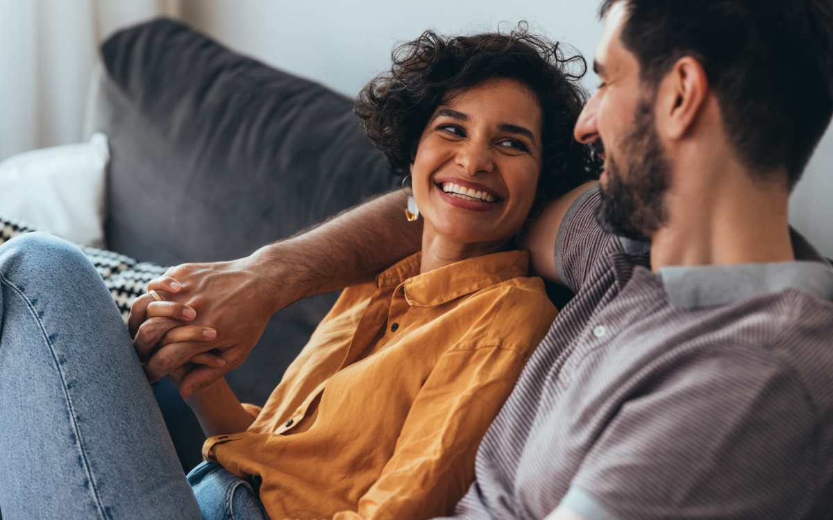 Happy residents sitting on a couch in the living room at Beacon Place at Kentlands in Gaithersburg, Maryland