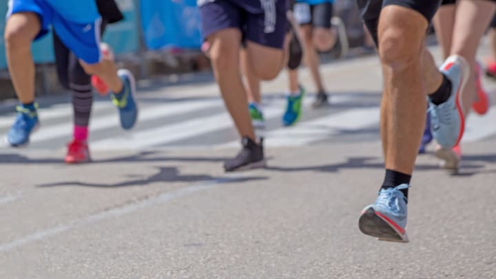 Low-perspective view of the legs and feet of a group of runners in a road race