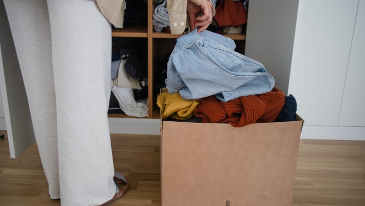 Person standing in front of a shelf with a box of clothing