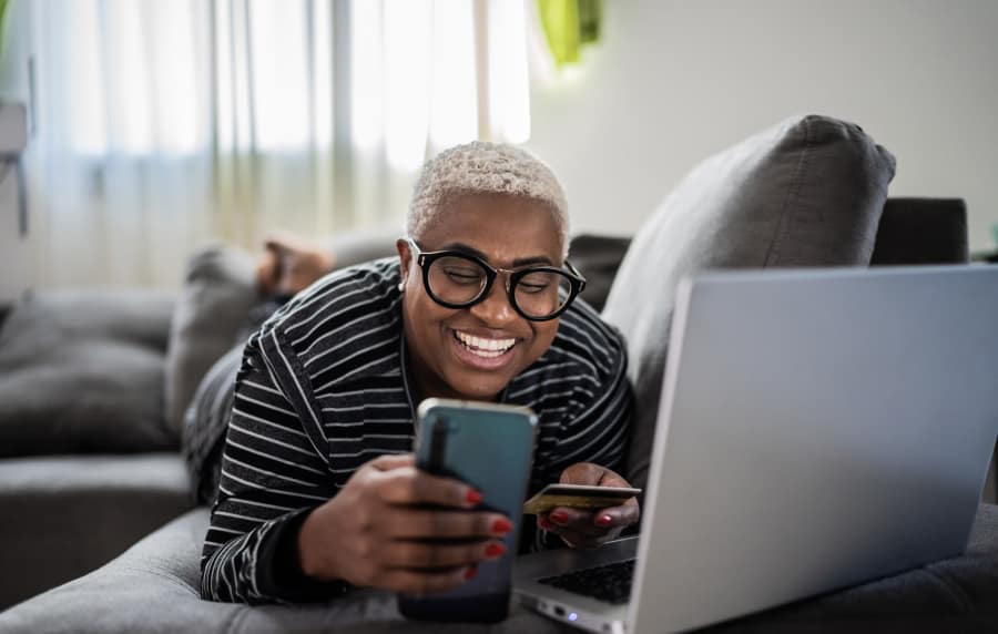 Resident checking his phone while working on his laptop at Charleston Square Apartments in Columbus, Indiana