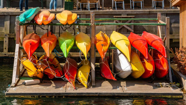 A picture of a group of colorful kayaks being kept near a canal.