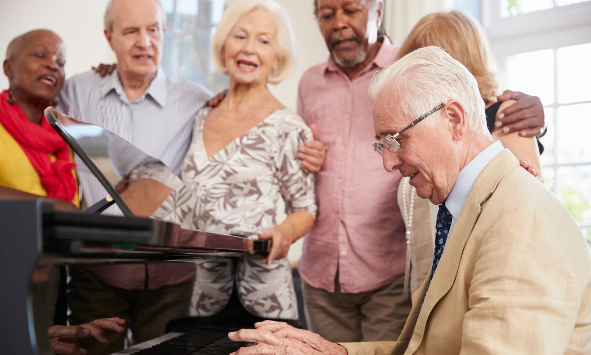 Residents playing the piano and singing at Avenir Memory Care at Surprise in Surprise, Arizona.