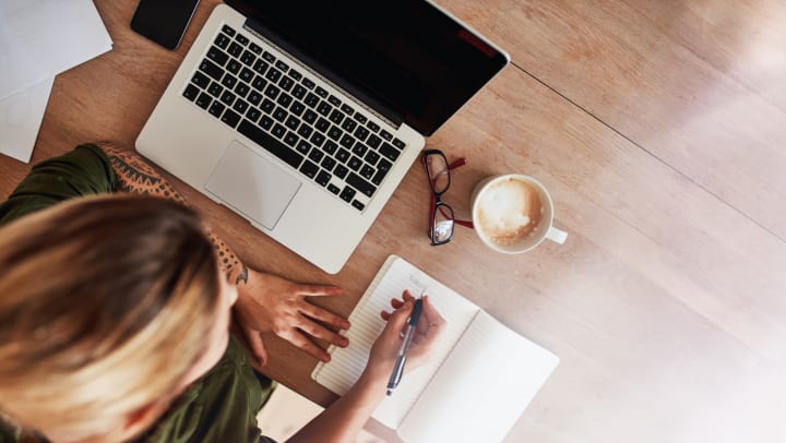 Student studying with a laptop, notebook, and cup of coffee