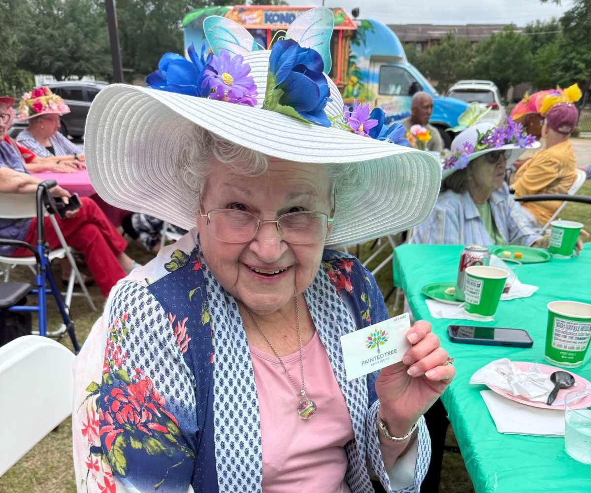 Resident with fancy hat poses for picture at Watercrest at Kingwood in Kingwood, Texas