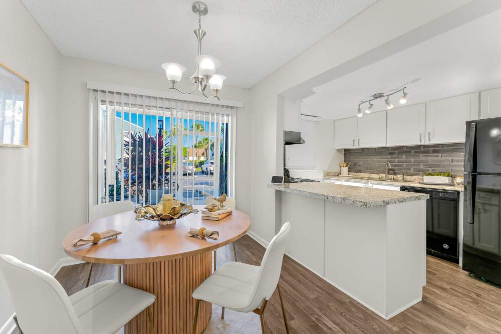Interior View Of A Dining Area With A Wooden Table, White Chairs, And A View Into The Kitchen at The Palms at Casselberry in Casselberry, Florida