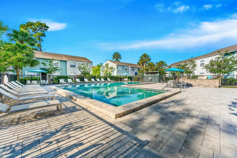 Exterior View Of A Community Swimming Pool Surrounded By Lounge Chairs And Landscaped Grounds at The Palms at Casselberry in Casselberry, Florida