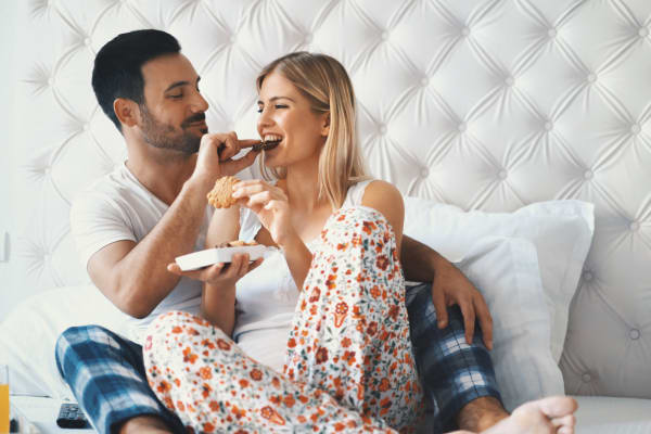 A couple enjoying a meal in bed at Hunt Club Apartments in Cockeysville, Maryland