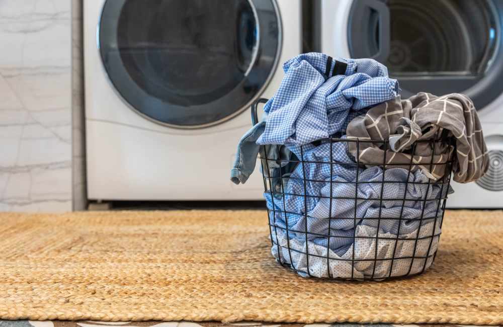 Laundry basket full of clothes near a washer and dryer at Parc at Prairie Grass Apartments in Colorado Springs, Colorado
