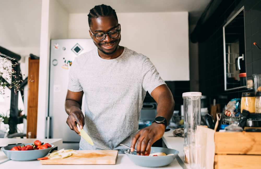 Resident chopping vegetables in his apartment kitchen at Creekwood Place in Lancaster, Texas