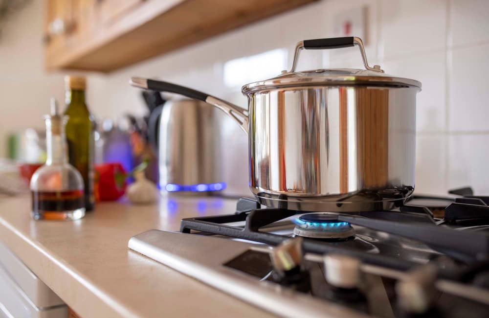 Stainless steel pot on a gas stove with granite countertop and kitchen accessories at Magnolia Crossing and Bell Ridge II in Pace, Florida