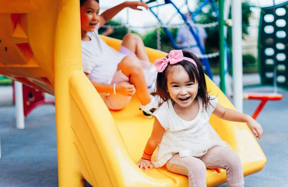 Children using a bright yellow playground slide at Fairway Ridge in Baltimore, Maryland 