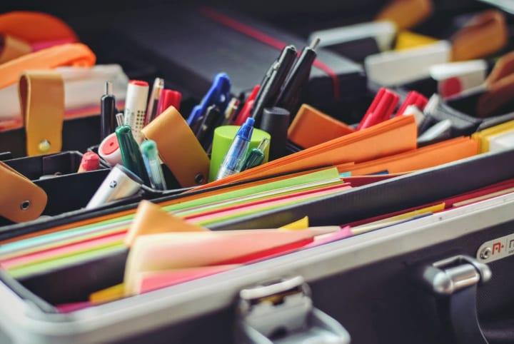 a container with pens, papers and other office supplies being organized