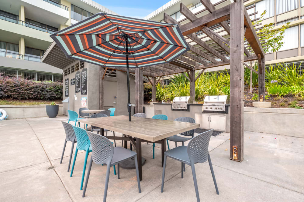 Sitting area by the pool with a table at Skyline Terrace Apartments in Burlingame, California
