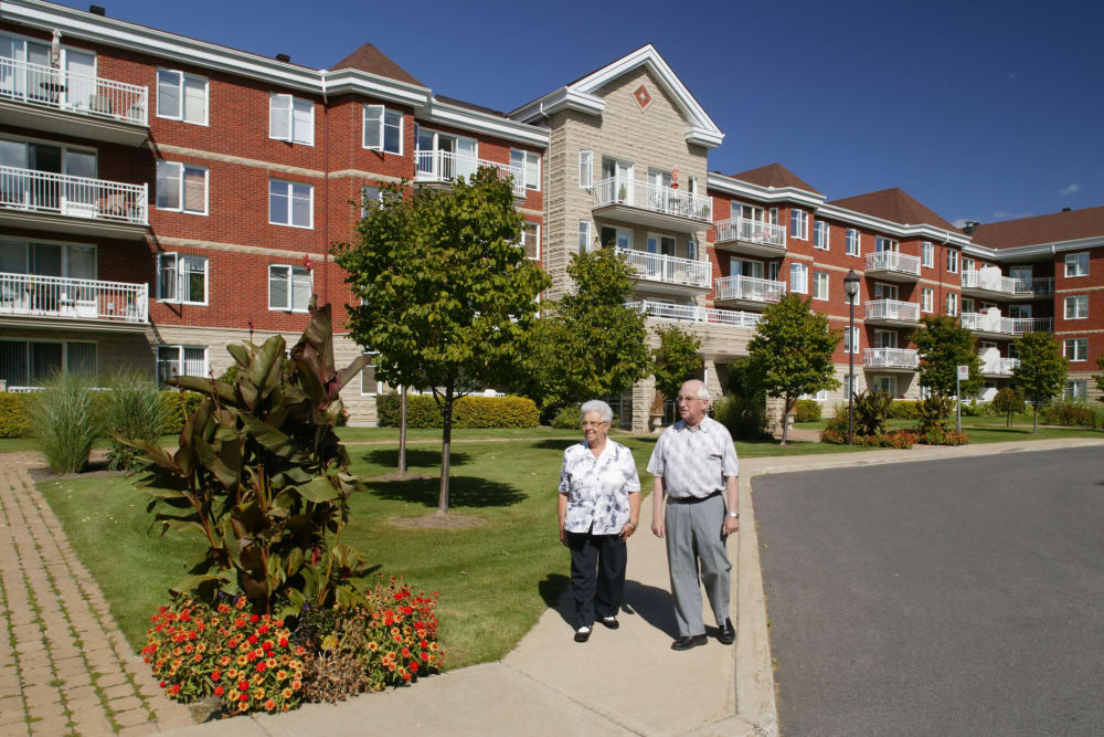 A couple walking outside apartments in a Virginia AgeWell Living community