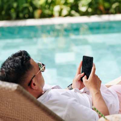Resident using phone while laying on a pool bed at The Heights at Waterpointe in Flowood, Mississippi