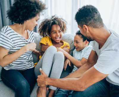 Happy family horsing around on the couch in their new apartment at Greece Commons Apartments in Rochester, New York