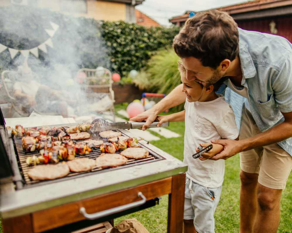 Father and son grilling together outdoors at The Residences at Talcott in Weatogue, Connecticut 