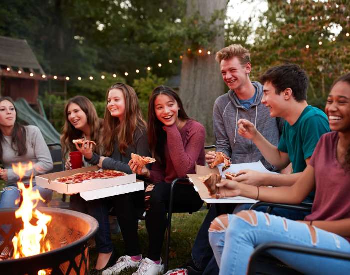 A group of smiling residents around a firepit outdoors near Avalon in Davis, California