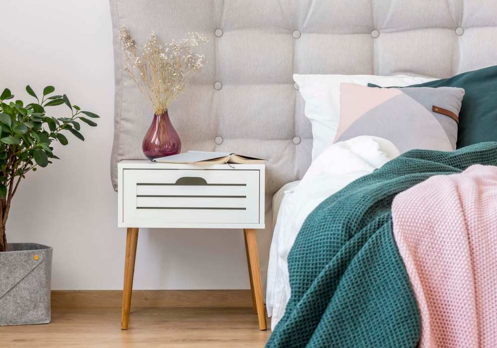 A cozy bed featuring a white headboard adorned with a soft pink blanket at EVOQ East Cobb in Marietta, Georgia