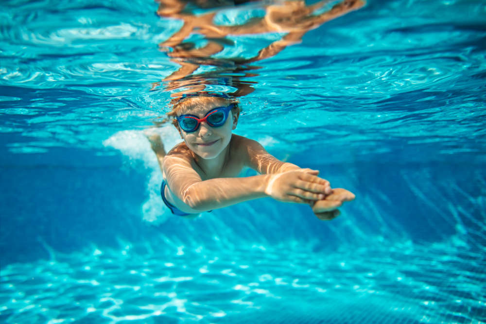 Kid enjoying a swim in the sparkling pool at Heron Creek Apartments in Moses Lake, Washington