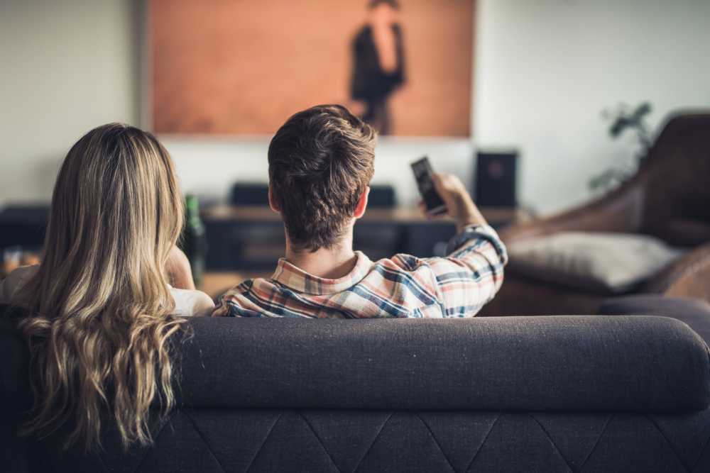 Couple relaxing on couch watching TV in a cozy living room at Covered Bridge in Indianapolis, Indiana 