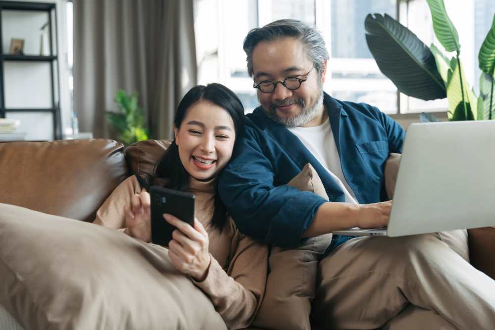 Couple enjoying leisure time on a couch with a smartphone and laptop at Central Avenue Lofts in Northeast Minneapolis, Minnesota 
