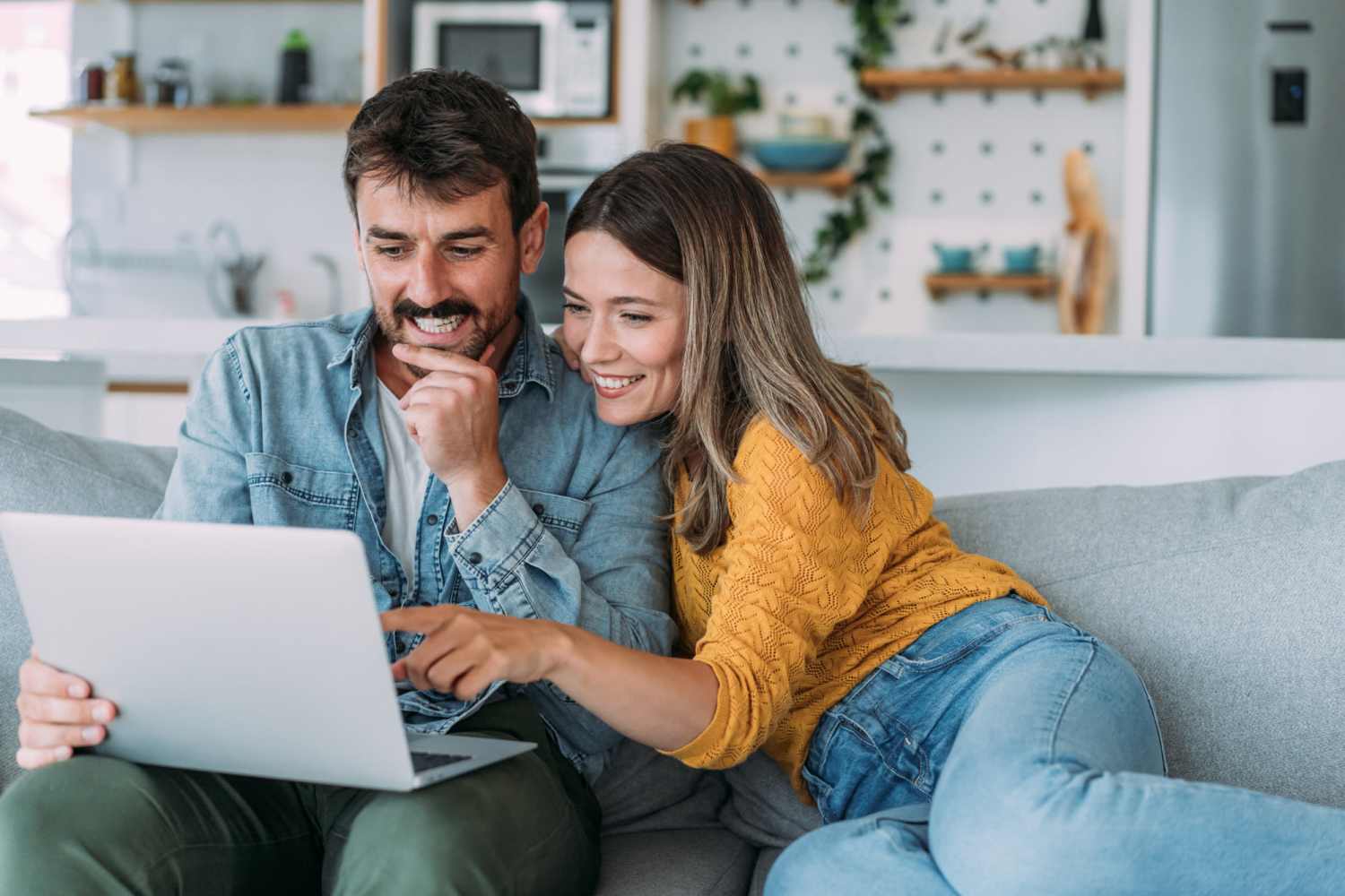A happy couple surfing the net while sitting on a couch atShipshewana Villas in Shipshewana, Indiana