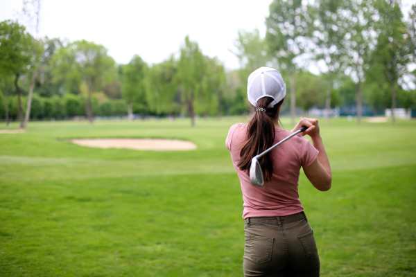 A woman plays golf on a well-maintained green field near Lofton Place in Tampa, Florida