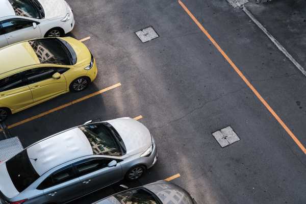 Parking lot with multiple cars, including a yellow car and several gray and white vehicles at Valley Brook Townhomes in Rochester, New York