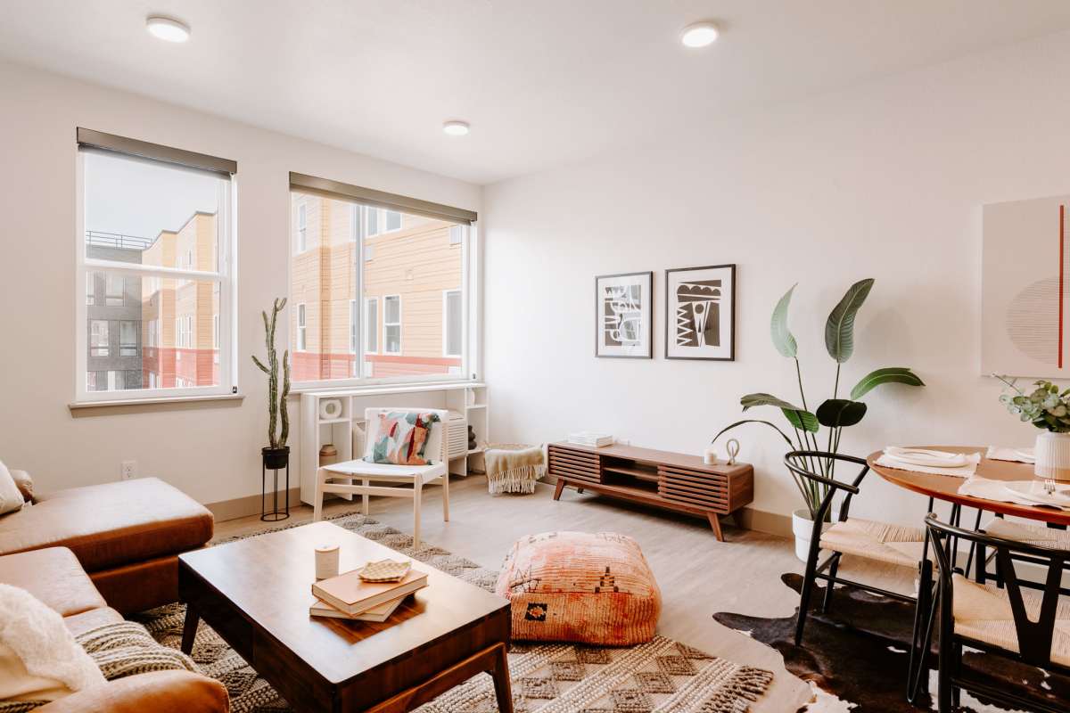 Bright living area with wood-style flooring, modern furnishings, and large windows showcasing outdoor views at Viña Apartments in Denver, Colorado 