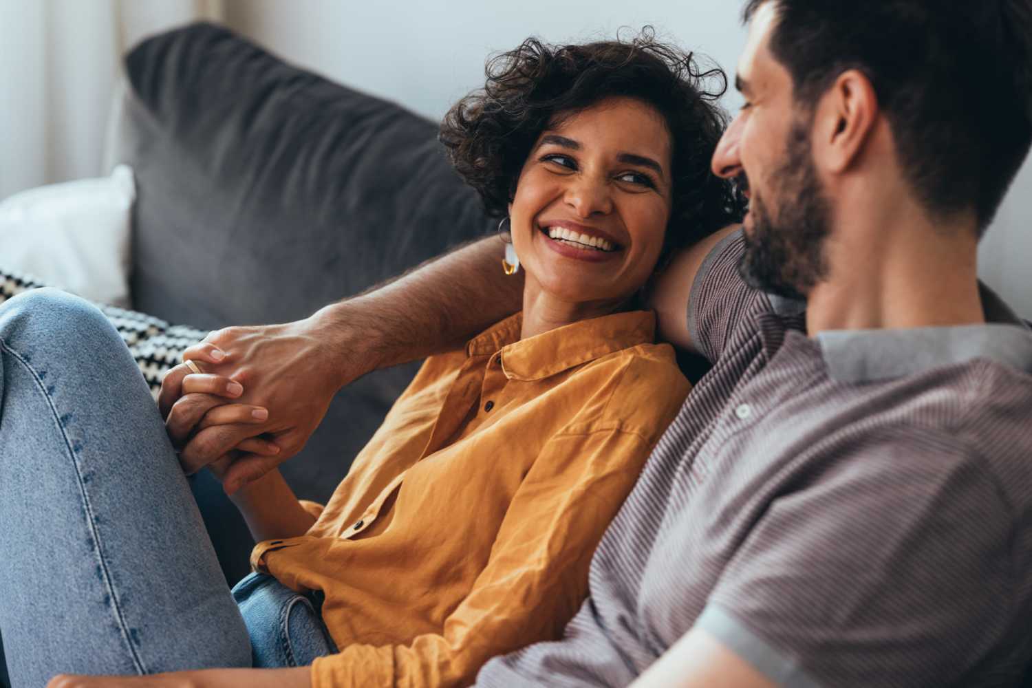 Happy couple sitting on couch in their new apartments at Taft Terrace in Taft, Texas