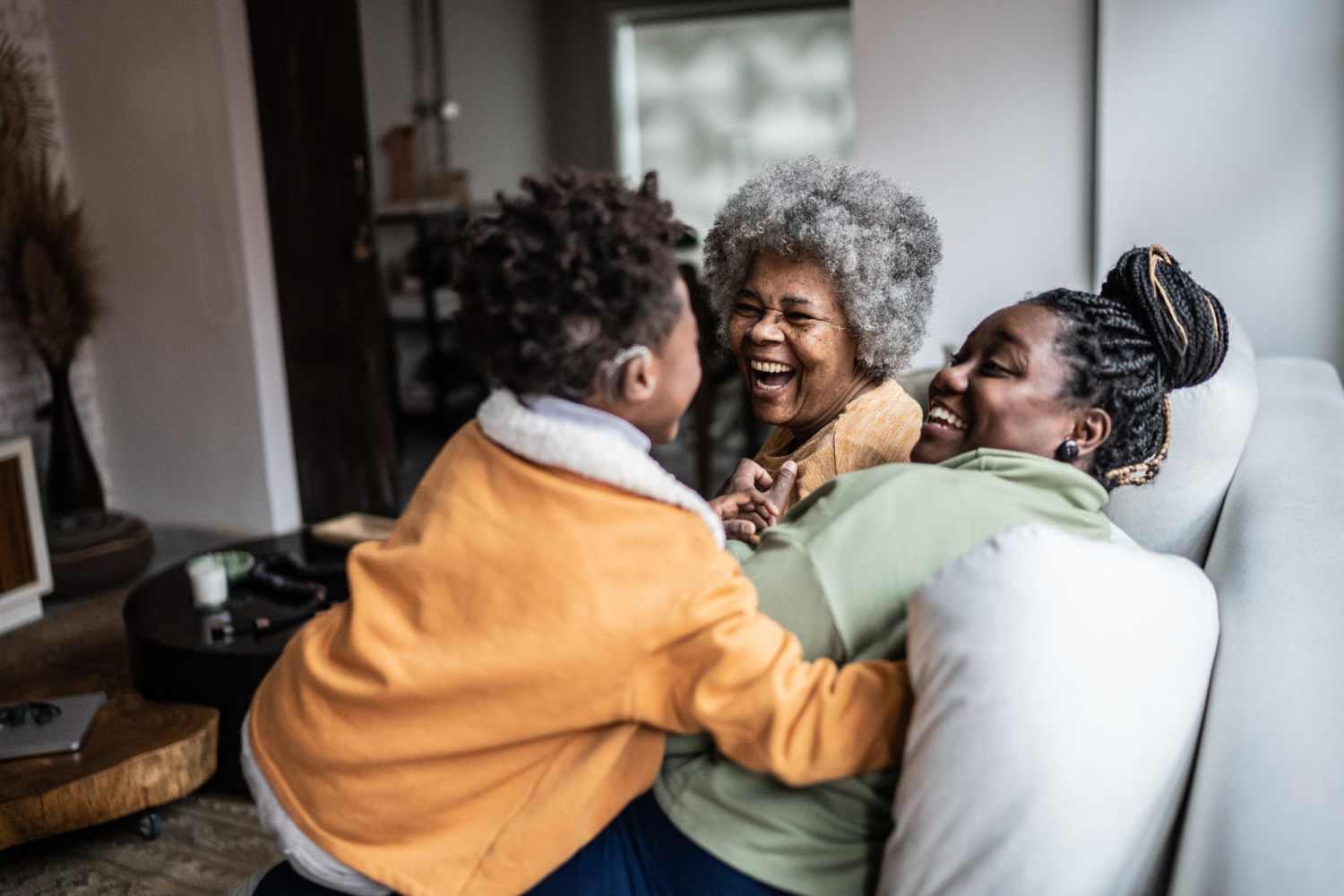 A happy family sitting on the couch and laughing in the living room at West Elm Villas in Wauseon, Ohio