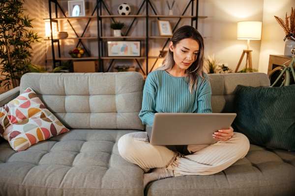 A resident sitting on the couch and working on her laptop in a modern living room at Prosper 83 in Sparks, Nevada