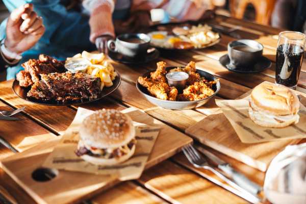 Table filled with various dishes including burgers, wings, fries, and drinks near Presidential Estates in Rochester, New York