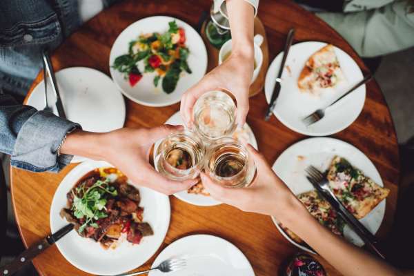Group of friends toasting with glasses over a table filled with various dishes at Valley Brook Townhomes in Rochester, New York