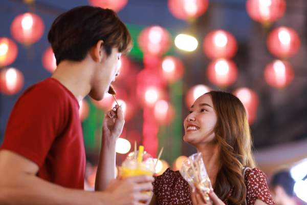 Couple enjoying drinks and snacks at a festive outdoor event with colorful lanterns hanging above at Reeves and Wells in Dallas, Texas 