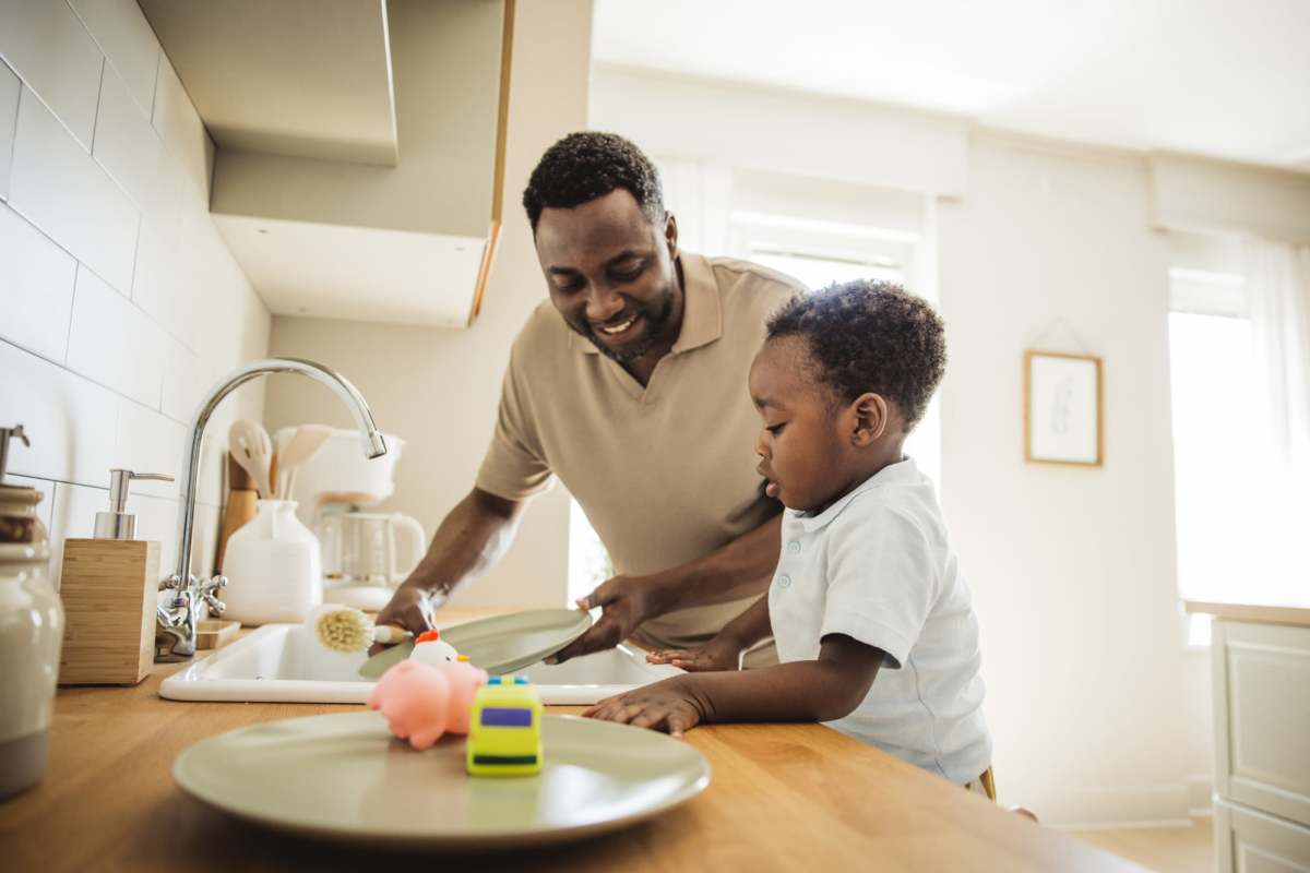 Father and son washing dishes in a modern kitchen with wood-style countertops at Atascocita Pines in Humble, Texas