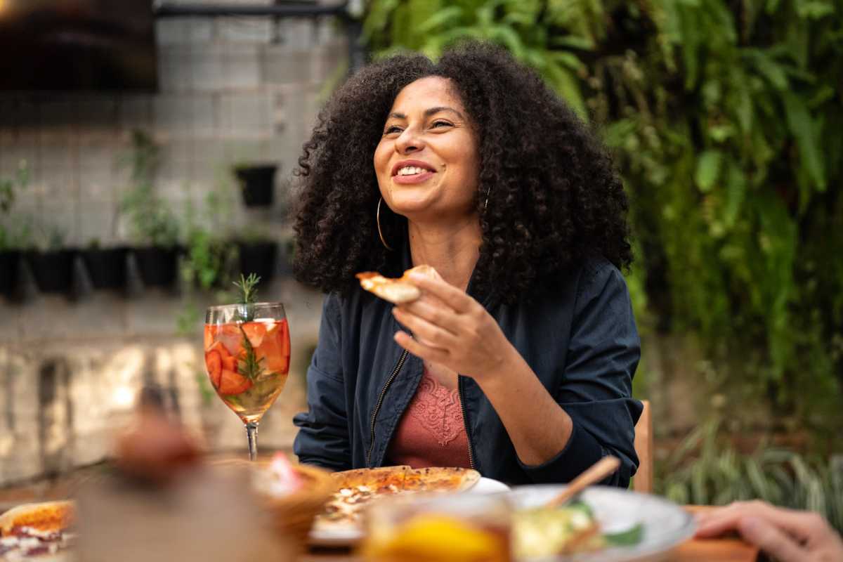 Woman enjoying pizza and drink at outdoor table near Shaw Estates in Jackson, Mississippi 