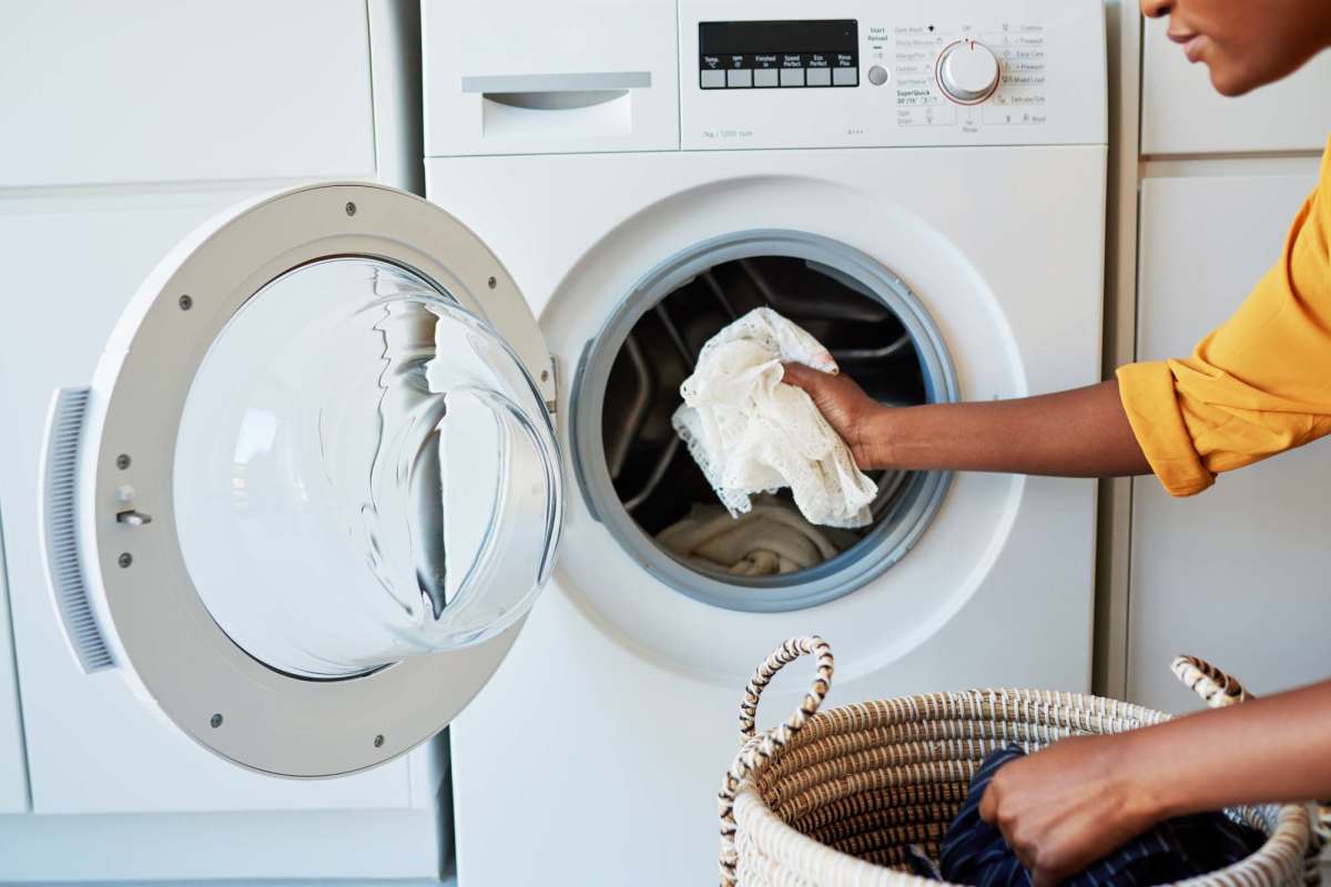 Woman loading laundry into front-loading washing machine at Windsor Gardens Apartments in Frederick, Maryland