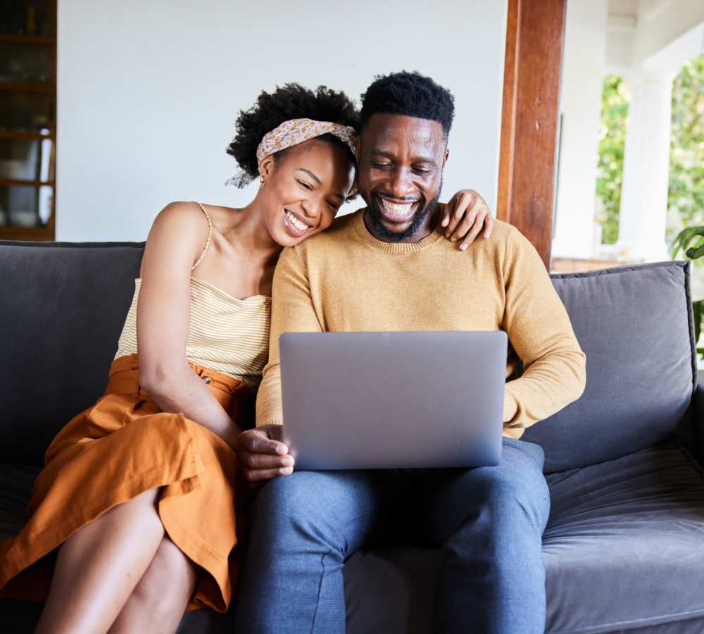 Couple smiling while using a laptop at Avia Lofts at Maple Road in Amherst, New York 