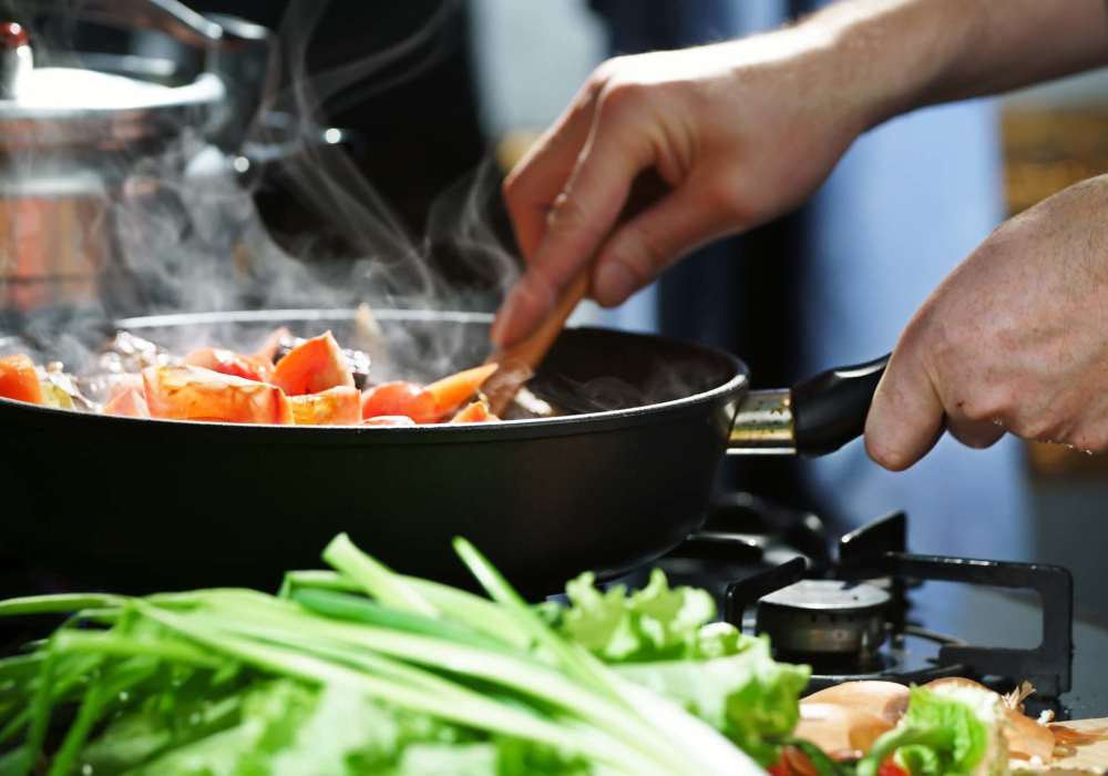 Resident cooking vegetables in a pan on a stovetop at North Road Townhomes in Scottsville, New York