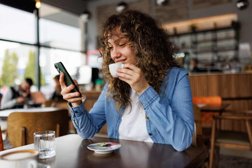Resident checking her phone while having coffee at a local restaurant near Andanté in Seattle, Washington
