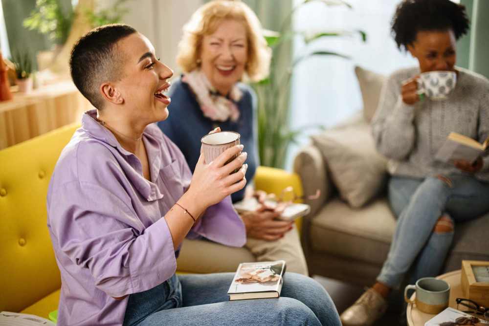 Three women enjoying coffee and laughter in the clubhouse with bright decor at The Havenly Gilbert in Gilbert, Arizona