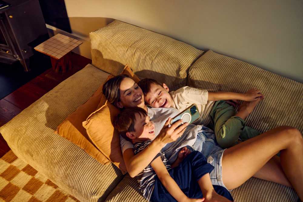 Woman and two children enjoying family time on a cozy sofa with a playful atmosphere at Mapleton Properties in Indianapolis, Indiana