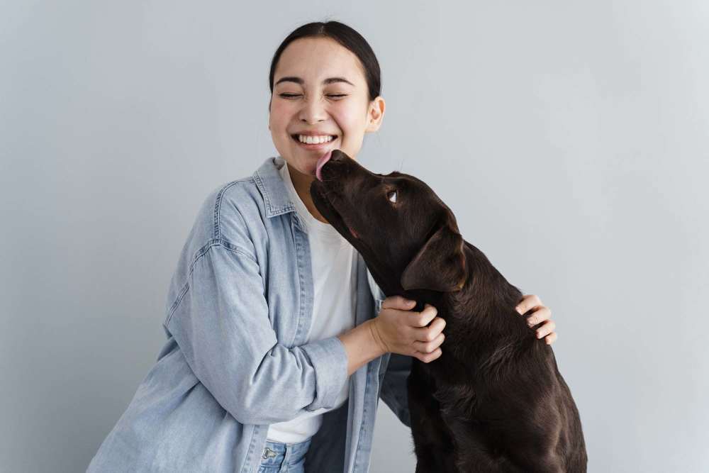 Woman smiling while playing with a brown dog in a cozy indoor setting at The Fielder in Austin, Texas 
