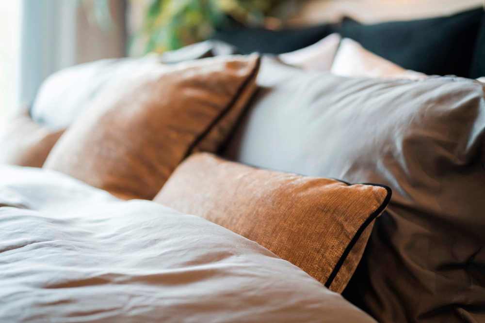 Soft, plush pillows on a neatly made bed with natural light filtering in at Covered Bridge in Indianapolis, Indiana