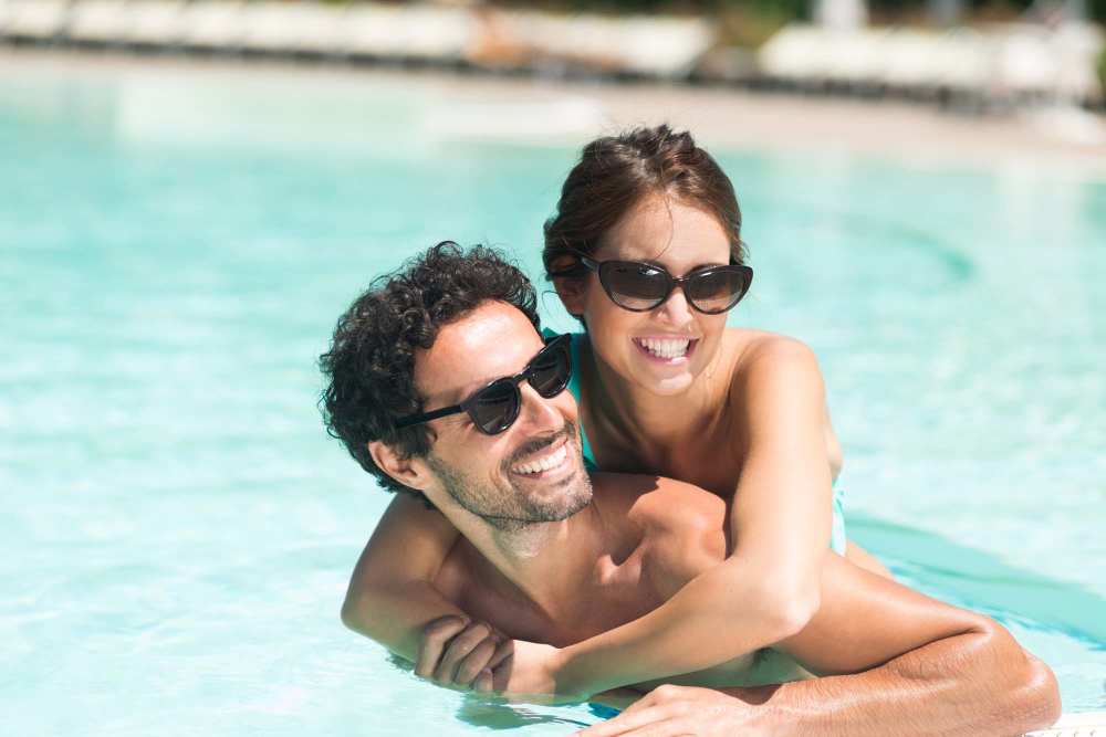 Couple enjoying a sparkling pool, smiling and relaxing together in warm sunlight at Covered Bridge in Indianapolis, Indiana 