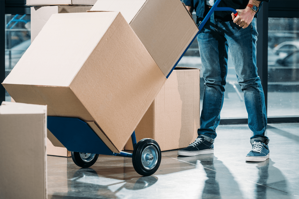 Man pushing dolly loaded with boxes at A-American Self Storage in Palmdale, California